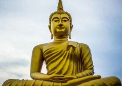 Golden Buddha statue under a serene sky in Thailand