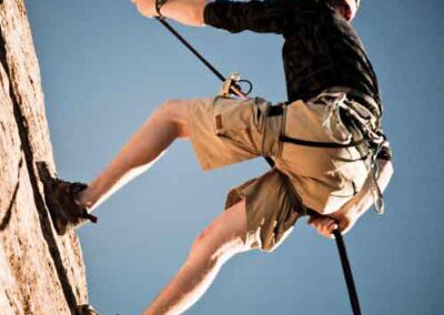 Rock climber scaling a vertical cliff under clear blue skies