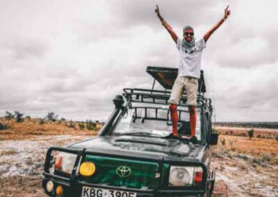 Safari adventurer standing on a jeep in the African wilderness