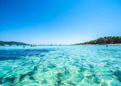 "Sunj Beach on Lopud Island with calm, crystal-clear waters and beachgoers enjoying the summer.